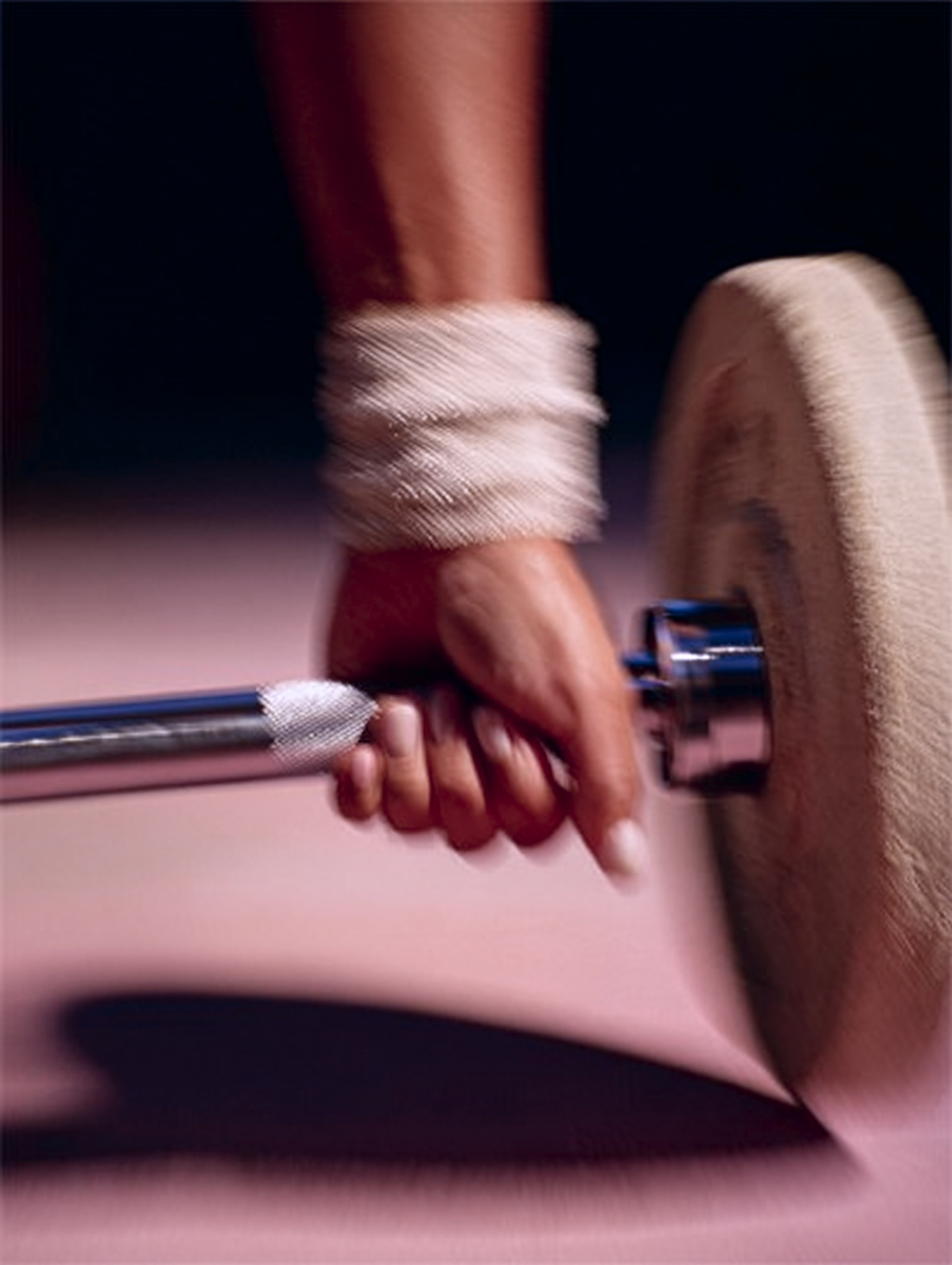 Eine geballte Hand umklammert eine Langhantel und demonstriert damit athletische Kraft und Entschlossenheit. Das Bild hat zur Verstärkung des Effekts leichte Bewegungsunschärfe.